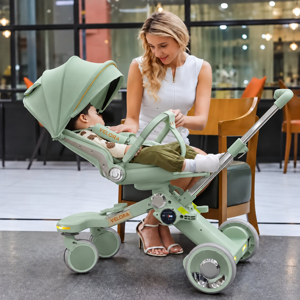 Toddler in the Green VELORA Electric Stroller with the 360-degree seat turned to face the parent